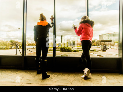 Two female friends looking out of window Stock Photo