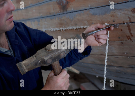 Man hammering string into boat in workshop Stock Photo