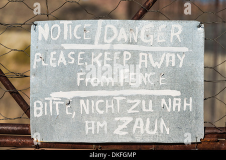 Warning sign in English and German on the fence of a predator enclosure, Namibia Stock Photo