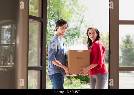 Young couple carrying cardboard box into new house Stock Photo