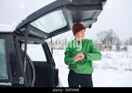 Female jogger preparing for run in snow covered scene Stock Photo