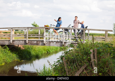 Family cycling over wood bridge Stock Photo