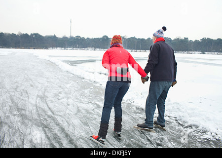 Couple ice skating, holding hands Stock Photo