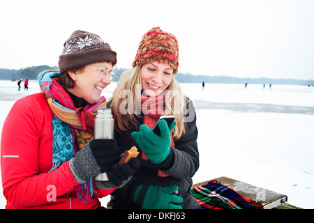 Women having hot drinking and looking at smartphone Stock Photo