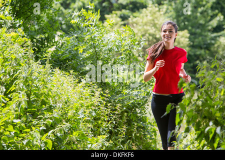 Woman jogging through forest Stock Photo