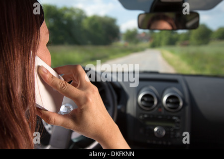A young woman is using a mobile phone while driving a car Stock Photo