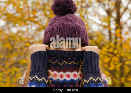 Close up portrait of young woman in park with jumper hiding face Stock Photo