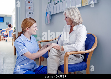 Mature female patient with nurse in hospital waiting room