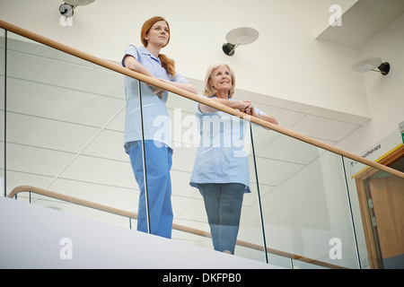 Two female nurses waiting on hospital atrium balcony Stock Photo