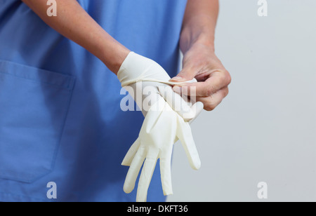 Surgeon putting on latex gloves Stock Photo