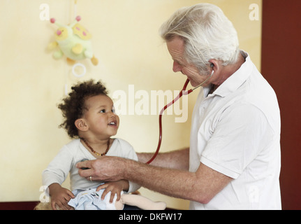 Paediatrician examining baby girl, using stethoscope Stock Photo