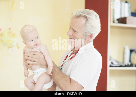 Paediatrician examining baby girl, holding baby Stock Photo