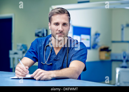 Portrait of male doctor writing up medical notes Stock Photo