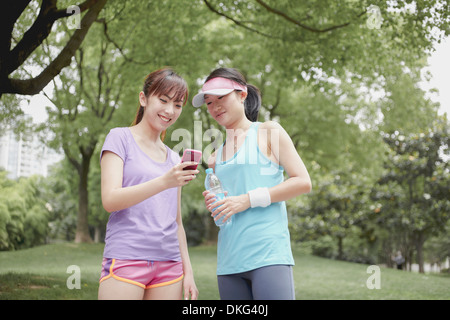 Female friends looking at cellphone in park Stock Photo