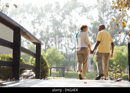 Senior couple walking on footbridge in park Stock Photo
