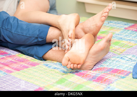 Close up of couples legs and feet on bed Stock Photo