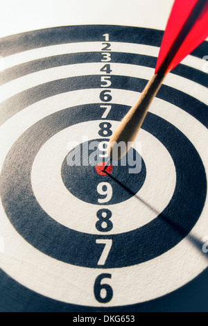 A wooden dart hits the center bullseye of a dartboard. Stock Photo