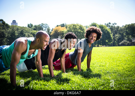 Three young men doing push ups in park Stock Photo
