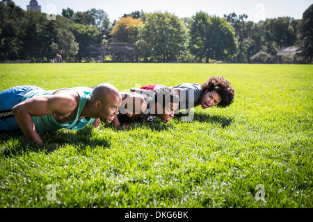 Three young men doing push ups in park Stock Photo