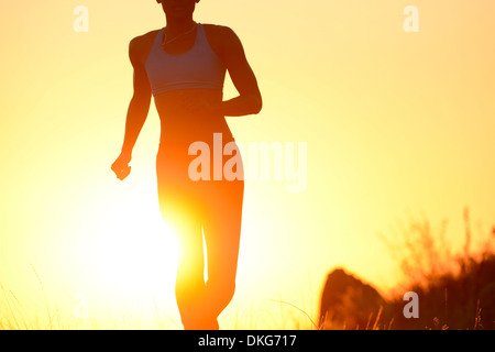 Silhouette of young woman running at sunset Stock Photo