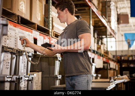 Worker in warehouse scanning barcode on cardboard box Stock Photo