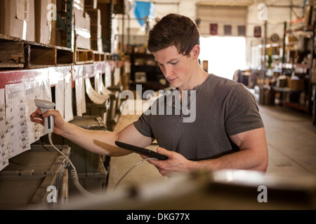 Worker in warehouse scanning barcode on cardboard box Stock Photo