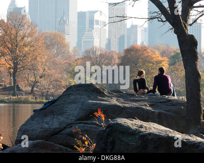 Young Couple Enjoying an Autumn Afternoon on Hernshead Promontory overlooking The Lake and Skyline, Central Park, NYC Stock Photo