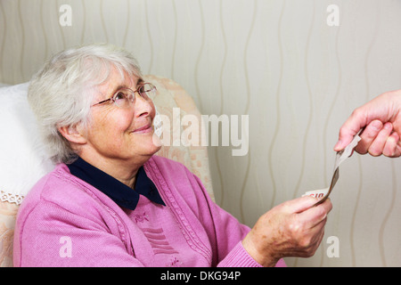 Happy senior woman pensioner OAP looking smiling at someone a carer and giving money to pay for help at home. Assisted living cost England UK Britain Stock Photo