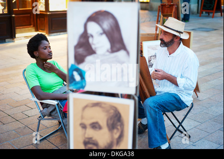 Unknown painters drawing the portraits of tourists at Old Town street of Bratislava Stock Photo