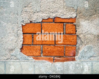 Old damaged rendering revealing inner wall of brick courses - France. Stock Photo