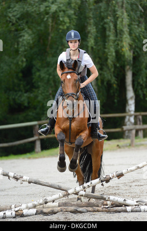 Teenage girl jumping with a Mecklenburger horse on a riding place Stock Photo