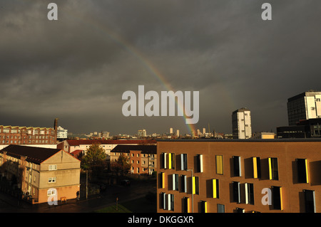 Dark brooding skies over Glasgow city centre lit up by sunshine and a rainbow Stock Photo
