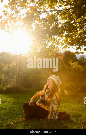 Smiling young woman playing guitar in autumn Stock Photo
