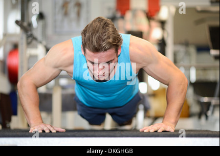 Young man doing push-ups in fitness center Stock Photo