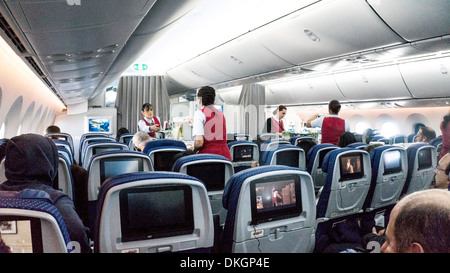 interior of Boeing 787 Dreamliner forward tourist cabin during in-flight meal service by uniformed AeroMexico flight attendants Stock Photo