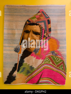 Hand made wall hanging of woven wool showing a portrait of an indigenous Peruvian man in colourful traditional dress and hat Stock Photo