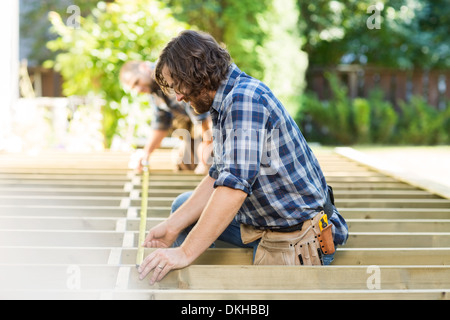 Mid Adult Carpenters Measuring Wood With Tape Stock Photo