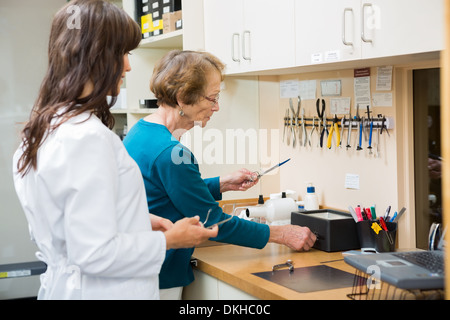 Optician With Apprentice Repairing Glasses In Workshop Stock Photo