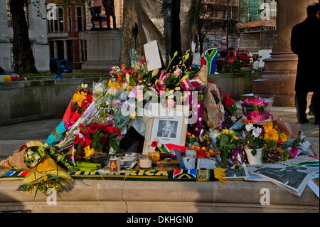 London, UK. 6th December 2013. Members of the public light candles,  lay flowers, wreaths, photographs, cards and South African flags at the base of the Nelson Mandela statue in London's Parliament Square in tribute to the late leader. Credit:  Pete Maclaine/Alamy Live News Stock Photo