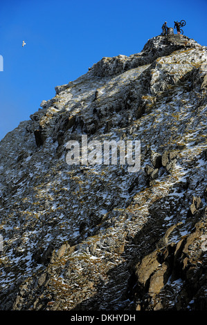 Two mountain bikers stand on the summit of Mount Snowdon in Snowdonia National Park. Stock Photo