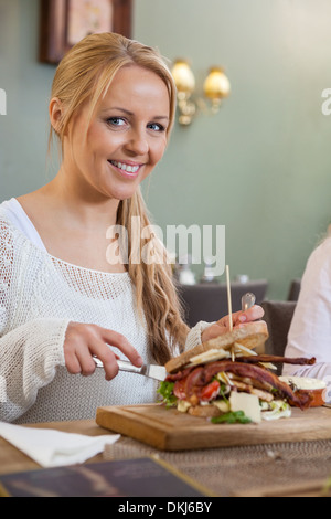 Young Woman Eating Sandwich In Restaurant Stock Photo