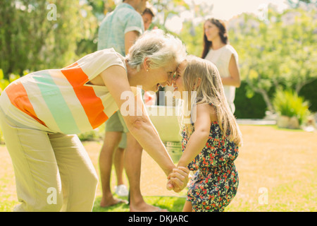 Grandmother and granddaughter rubbing noses in backyard Stock Photo