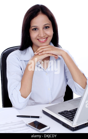 Smiling young business woman working with laptop against white Stock Photo