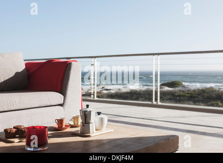 Breakfast on coffee table on modern patio overlooking ocean Stock Photo