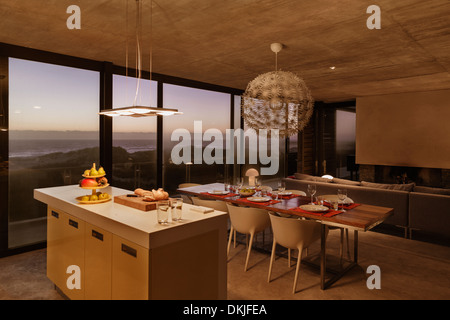 Breakfast bar and dining table in modern kitchen overlooking ocean at dusk Stock Photo