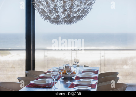 Set table in modern dining room overlooking ocean Stock Photo