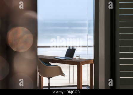 Laptop on desk in modern home office overlooking ocean Stock Photo