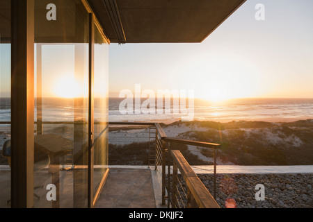 View of sunset over ocean from balcony of modern house Stock Photo