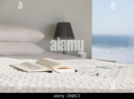 Book and glasses on bed in modern bedroom with ocean view Stock Photo