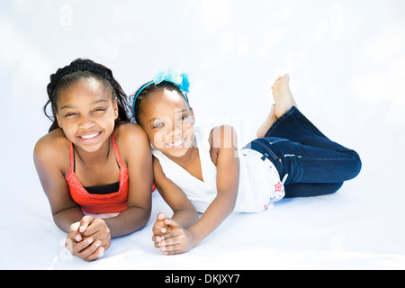 Two happy young sisters laying down on white background Stock Photo